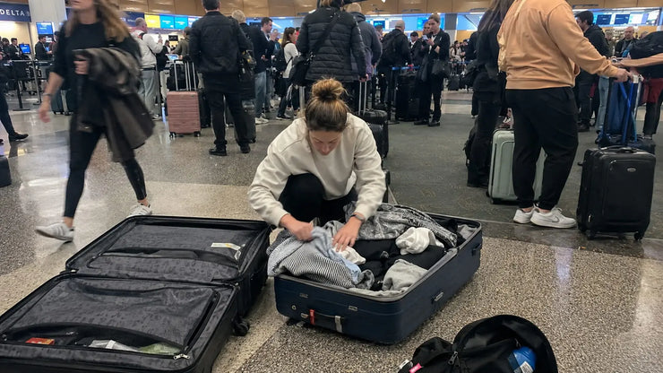 Woman reorganizing luggage at airport to avoid overweight fee