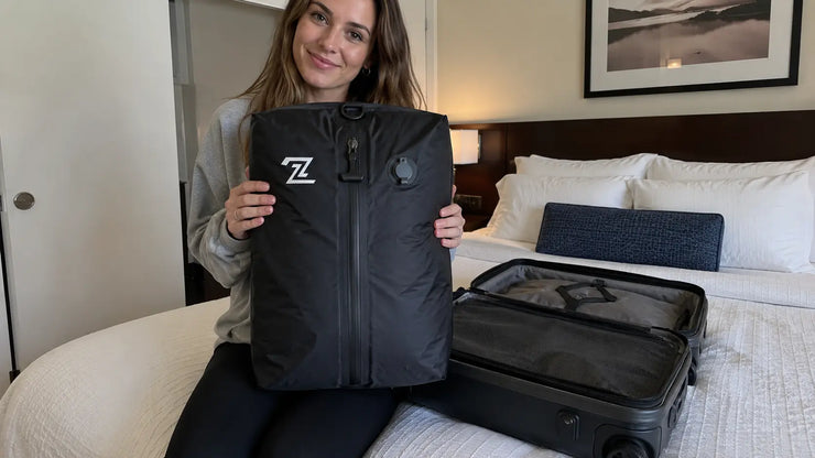 Amanda holding 2PackBag in hotel room next to carry-on suitcase